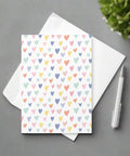 Pastel hearts greeting card with white envelope and pen