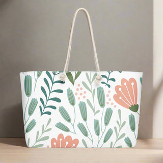 Large pink and green botanical print travel tote on a wooden surface