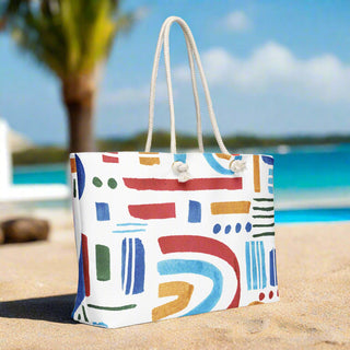 Oversized rainbow tote with rope handles styled for summer beach travel