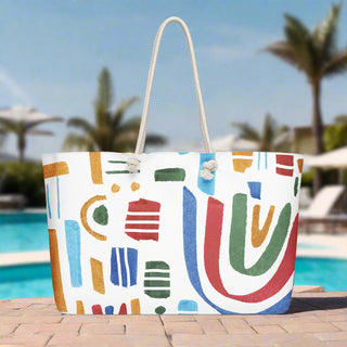 Oversized tote bag with abstract rainbow and colorful shapes, styled poolside