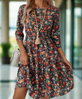 Woman wearing ruched floral dress with round neckline and 3/4 sleeves