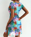 Woman wearing a colorful tropical print dress against a white background