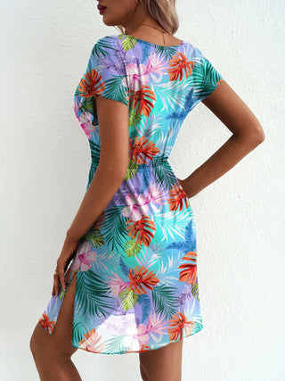 Woman wearing a colorful tropical print dress against a white background