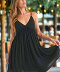 Woman wearing ruched plunge mini sun dress in black outdoors