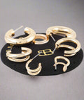 Flat lay of multiple pairs of shiny hoop earrings in gold and silver