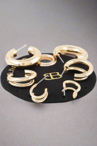 Flat lay of multiple pairs of shiny hoop earrings in gold and silver