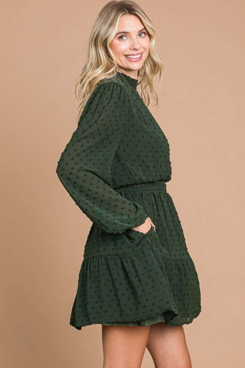 Side profile of the Swiss dot mini dress in green, featuring long sleeves and pockets.