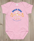 Pink baby onesie with 'Snack Boss' graphic on a wooden surface