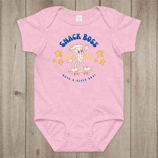 Pink baby onesie with 'Snack Boss' graphic on a wooden surface