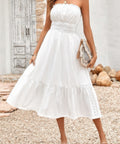Closeup of woman wearing strapless smocked white midi dress with flowy skirt