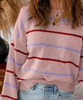 Woman wearing a pink striped round neck drop shoulder sweater with relaxed fit