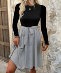 Woman wearing black top and striped skirt tie-waist dress