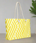 Back view of oversized yellow weekender tote with rope handles and decorative plant background