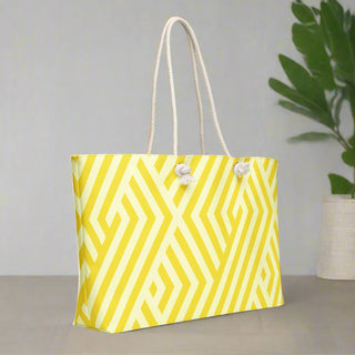 Back view of oversized yellow weekender tote with rope handles and decorative plant background