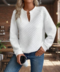 Model wearing a white textured notched raglan sleeve sweatshirt styled with jeans in a casual café