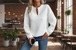 Model wearing a white textured notched raglan sleeve sweatshirt styled with jeans in a casual café