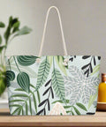 Oversized canvas tote bag with green tropical leaf and botanical print on a kitchen counter