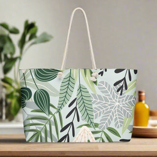 Oversized canvas tote bag with green tropical leaf and botanical print on a kitchen counter