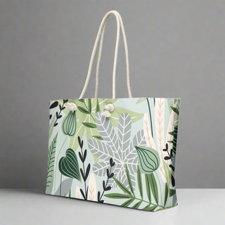 Large canvas travel tote bag featuring green jungle leaves and white tropical foliage

