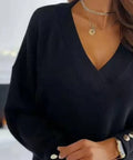 Angled view of black V-neck sweater with decorative buttons on sleeve cuffs