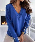 Angled view of bright blue V-neck sweater styled casually with jeans