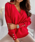 Woman wearing a red V-neck decorative button sweater styled with neutral pants