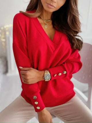 Woman wearing a red V-neck decorative button sweater styled with neutral pants