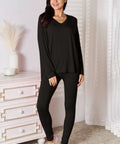 Model wearing a black V-neck long sleeve lounge set with matching pants, styled for casual comfort.