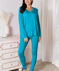 Model wearing a blue V-neck long sleeve lounge set with matching pants, styled in a casual indoor setting.