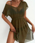 Woman wearing a green sheer bathing suit coverup against a white background