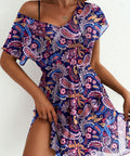 Woman wearing a colorful paisley dress against a white background