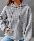 Woman wearing gray waffle knit pullover hoodie with jeans