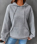 Woman wearing gray waffle knit pullover hoodie with jeans