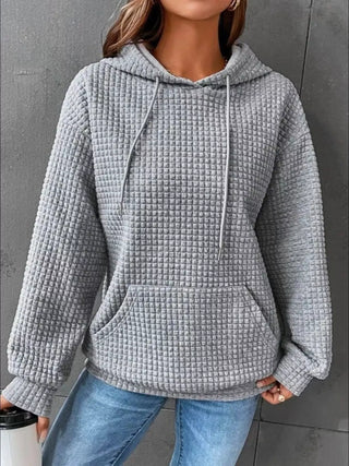 Woman wearing gray waffle knit pullover hoodie with jeans