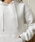 Close-up of white waffle hoodie fabric texture and drawstrings