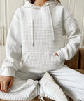 Woman wearing white waffle knit pullover hoodie, front view