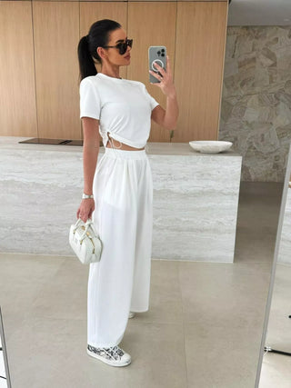 white matching two piece travel outfit featuring crop top and wide leg pants