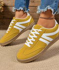 Woman wearing yellow lace-up sneakers styled with cropped denim jeans for a casual weekend outfit.